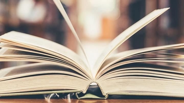 Book lies open on a table in a library. 