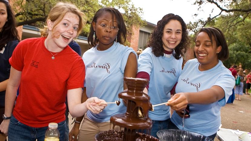 four women pose by a chocolate fountain